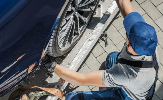 automobile towing worker securing car on his tow t 3UUYXQK