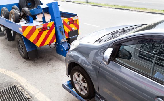 tow truck towing a broken down car on the street P2HVPC8