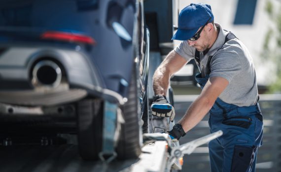 towing company worker securing vehicle on the truc J69LFXZ